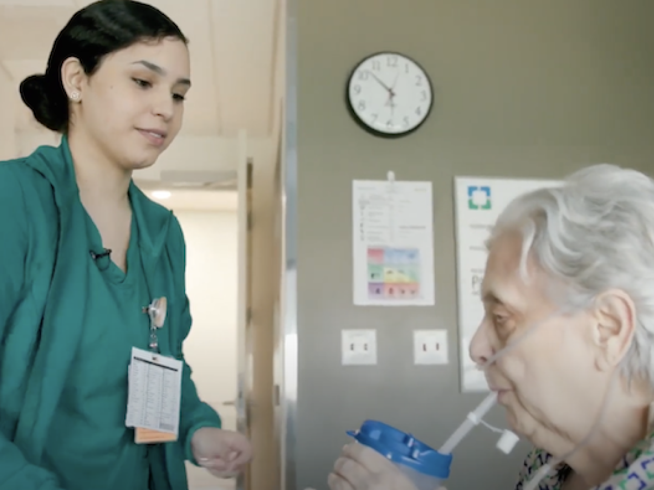 A nurse is assisting a patient with a beverage.